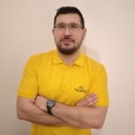 muž se založenýma rukama ve žlutém tričku s logem firmy Nanto